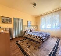 Schlafzimmer in einem Einfamilienhaus mit Holzboden, großem Fenster und Teppichen.