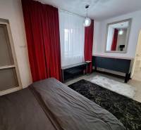 Das Innere eines Einfamilienhauses mit roten Vorhängen, einem Spiegel und einem dunklen Teppich.