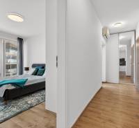 Schlafzimmer mit großem Fenster und Flur mit Holzboden in einer 2-Zimmer-Wohnung.