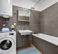 Badezimmer in einer 2-Zimmer-Wohnung mit Waschmaschine, Badewanne, Waschbecken und Gaskessel.