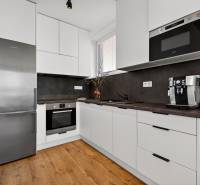 Küche in einer 2-Zimmer-Wohnung mit Holzboden, weißen Schränken, Geräten.