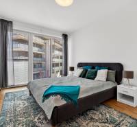Schlafzimmer mit großem Bett, Balkontüren und Holzboden in einer 2-Zimmer-Wohnung.