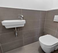 Badezimmer mit Waschbecken und Toilette in einer 2-Zimmer-Wohnung mit einfachen Fliesen.