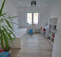 Kinderzimmer in einem Einfamilienhaus mit Bett, Tisch und Regal auf einem Boden mit Holzdekor.