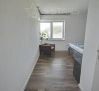 Ein Zimmer in einem Einfamilienhaus mit einem Holzboden, einem Sessel und einem Fenster.