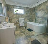 Badezimmer mit einer Duschkabine aus Glas und einer Badewanne in einem Einfamilienhaus.