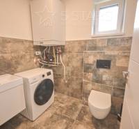 Badezimmer in einem Einfamilienhaus mit Waschbecken, Waschmaschine und Toilette.