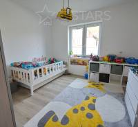 Kinderzimmer mit Bett, Spielzeug, Teppich mit Giraffenmotiv, Boden mit Holzdekor.