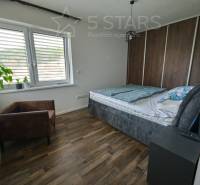 Schlafzimmer in einem Einfamilienhaus mit Bett, Sessel und Boden in Holzoptik.