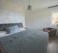 Schlafzimmer in einem Einfamilienhaus mit einem Bett mit textiler Kopfstütze und einem Boden mit Holzdekor.