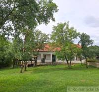 Ein Einfamilienhaus in Dobroč mit weißer Fassade und rotem Dach, umgeben von Grün.