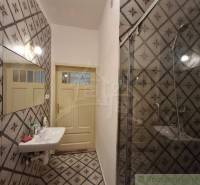 Badezimmer mit gefliester Wand, Spiegel, Waschbecken und Dusche in einem Einfamilienhaus.
