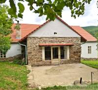 Ein Einfamilienhaus in Dobroč mit einer Steinfasade, einem traditionellen Dach und einem gemütlichen Garten.