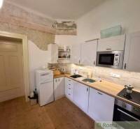Küche in einem Einfamilienhaus mit weißen Schränken und einem Boden in Holzoptik.