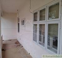 Ein Einfamilienhaus in Mužla mit einer durchgehenden Terrasse, Fenstern mit Jalousien und einem Betonboden.