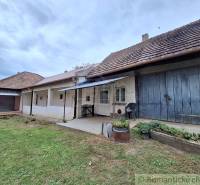 Ein Einfamilienhaus in Mužla mit traditioneller Fassade, Veranda und einem üppigen Garten.