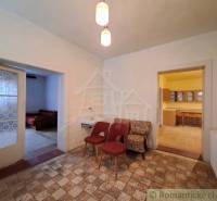 Interieur eines Einfamilienhauses mit Sesseln, Waschbecken, Küche und zwei offenen Türen.