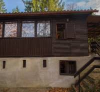 Eine Holzhütte auf Erholungsgrundstücken in Holčíkovce, umgeben von Grün und Bäumen.