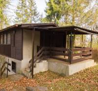 Eine Holzhütte auf Erholungsgrundstücken in Holčíkovce, umgeben von Bäumen und gefallenem Laub.