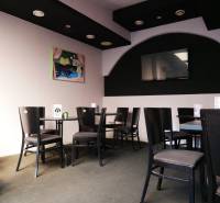 Gasträume mit schwarzen Stühlen, Kunst an der Wand und einem Fernseher.