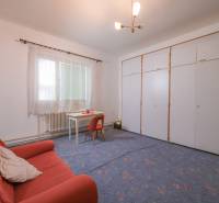 Das Einfamilienhaus enthält ein Wohnzimmer mit Teppichboden, ein oranges Sofa und einen weißen Tisch.