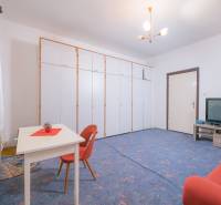 Wohnzimmer in einem Einfamilienhaus mit blauem Teppich, ausziehbarem Sofa und Aufbewahrungsschränken.
