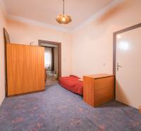 Ein Zimmer in einem Einfamilienhaus mit blauem Teppich, Holzmöbeln und einem Bett.