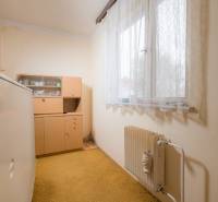 Ein Zimmer in einem Einfamilienhaus mit älteren Möbeln, einem Heizkörper und einem Teppich.
