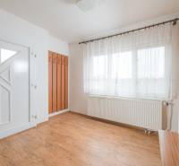 Innenraum eines Einfamilienhauses mit weißen Wänden, Fenstern und einem Boden in Holzoptik.