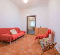 Wohnzimmer mit rotem Sofa, Sessel, Zeitschriften und Holzboden in einem Einfamilienhaus.