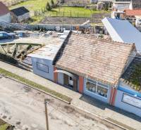 Geschäftsräume in Okoč mit traditionellem Dach, Gehweg und Garten.