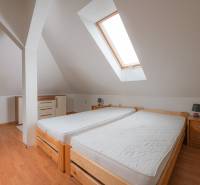 Dachbodenschlafzimmer mit zwei Einzelbetten und Holzboden in einer Zweizimmerwohnung.