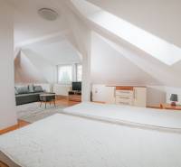 Innenraum einer 2-Zimmer-Wohnung mit Bett, Sofa und Boden in Holzoptik.
