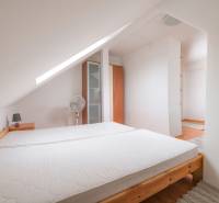 Dachbodenschlafzimmer in einer 2-Zimmer-Wohnung mit Bett und Schrank, Teppichboden.