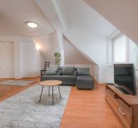 Wohnzimmer in einer Zweizimmerwohnung mit grauem Sofa und Holzboden.