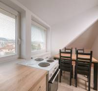 Küche in einer 2-Zimmer-Wohnung mit Herd, Mikrowelle und Esstisch, mit Blick auf die Stadt.