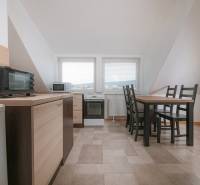 Küche in einer 2-Zimmer-Wohnung mit Esstisch, Geräten und Fliesen.