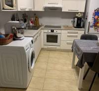 Küche in einer 2-Zimmer-Wohnung mit weißen Schränken und Keramikboden.