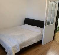 Schlafzimmer in einer 2-Zimmer-Wohnung mit Holzboden und einem großen Bett.