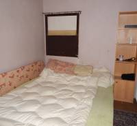 Zimmer mit Bett, Regal und Heizkörper, geeignet für Gastronomiebereiche zur Renovierung.