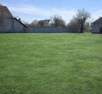 Der Garten in Dolná Seč, umgeben von Einfamilienhäusern und einem Zaun unter blauem Himmel.