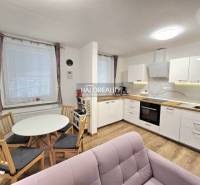 Küche in einer 3-Zimmer-Wohnung mit weißen Schränken, Boden in Holzoptik und kleinem Tisch.