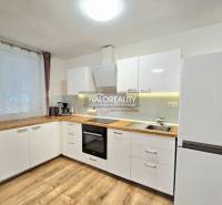 Küche in einer 3-Zimmer-Wohnung mit weißen Schränken und einem Boden in Holzoptik.