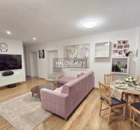 Wohnzimmer in einer 3-Zimmer-Wohnung mit Fernseher, rosa Sofa und Tisch.