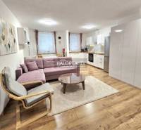 Wohnzimmer in einer 3-Zimmer-Wohnung mit Holzboden, Sofa und Küche.
