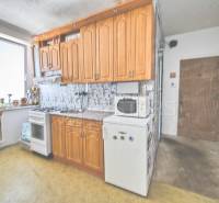 Küche mit Holzschränken und Geräten in einer Einzimmerwohnung.