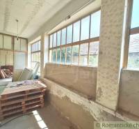 Eine Hütte mit einer geräumigen Veranda, großen Fenstern und vielfältigem gelagertem Material.