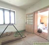 Ein Raum in einer Hütte mit Licht aus dem Fenster, offenen Türen und Baustellenunordnung.