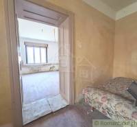 Ein Zimmer in einer Hütte mit alten Möbeln und einem Fenster wartet auf die Renovierung.