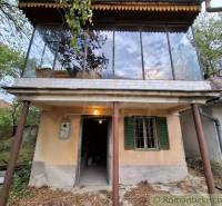 Ein Ferienhaus in Kamenín mit einer verglasten Terrasse, umgeben von Natur und Bäumen.